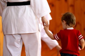Woman karate kimono holds her child's hand